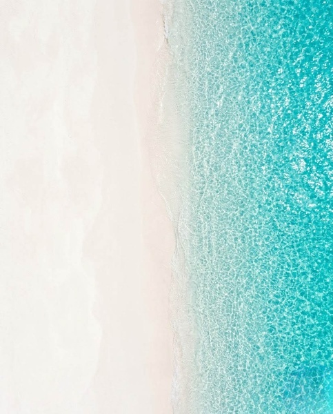 Vue aérienne d'une plage de sable blanc et d'une mer turquoise cristalline.