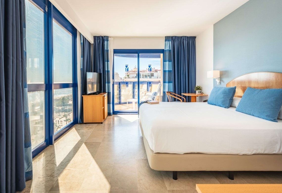 a hotel room with a king size bed and blue curtains