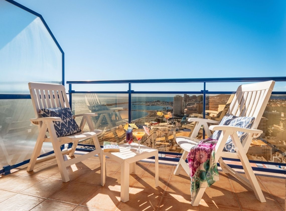 a balcony with two chairs and a table with a drink on it