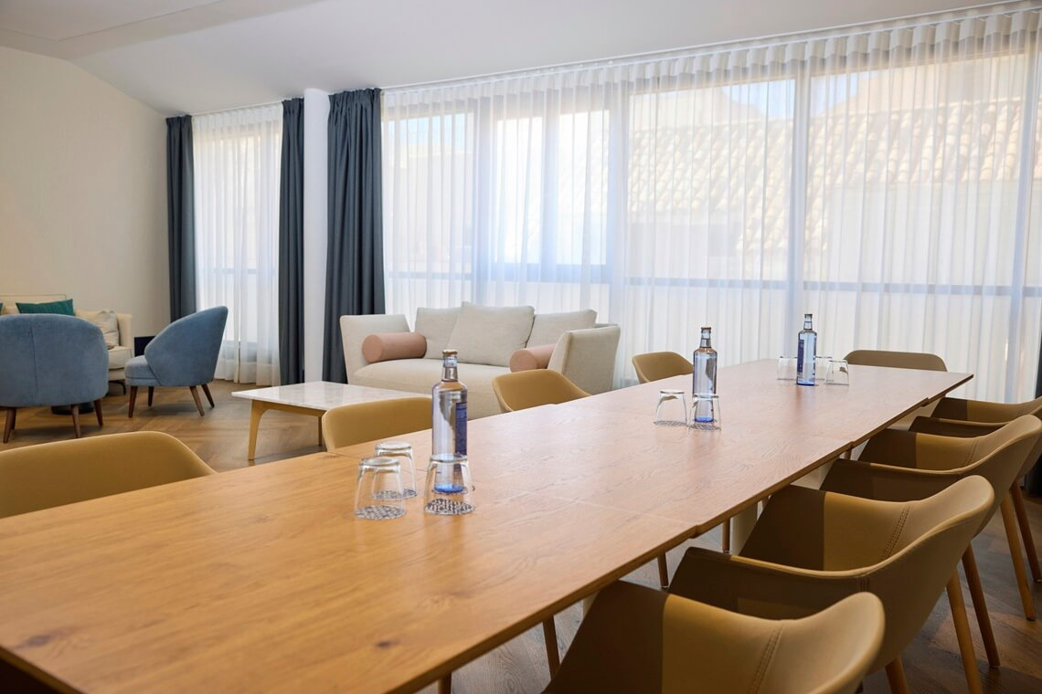 Nautical Lounge Nautical Lounge Corporate dining room in a hotel with a long wooden table, beige chairs, and large windows. Yaramar