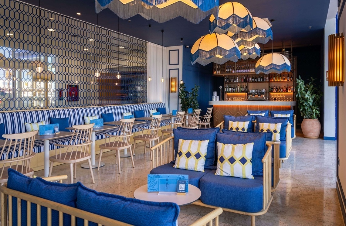 une salle à manger bleue et blanche avec des canapés et des tables