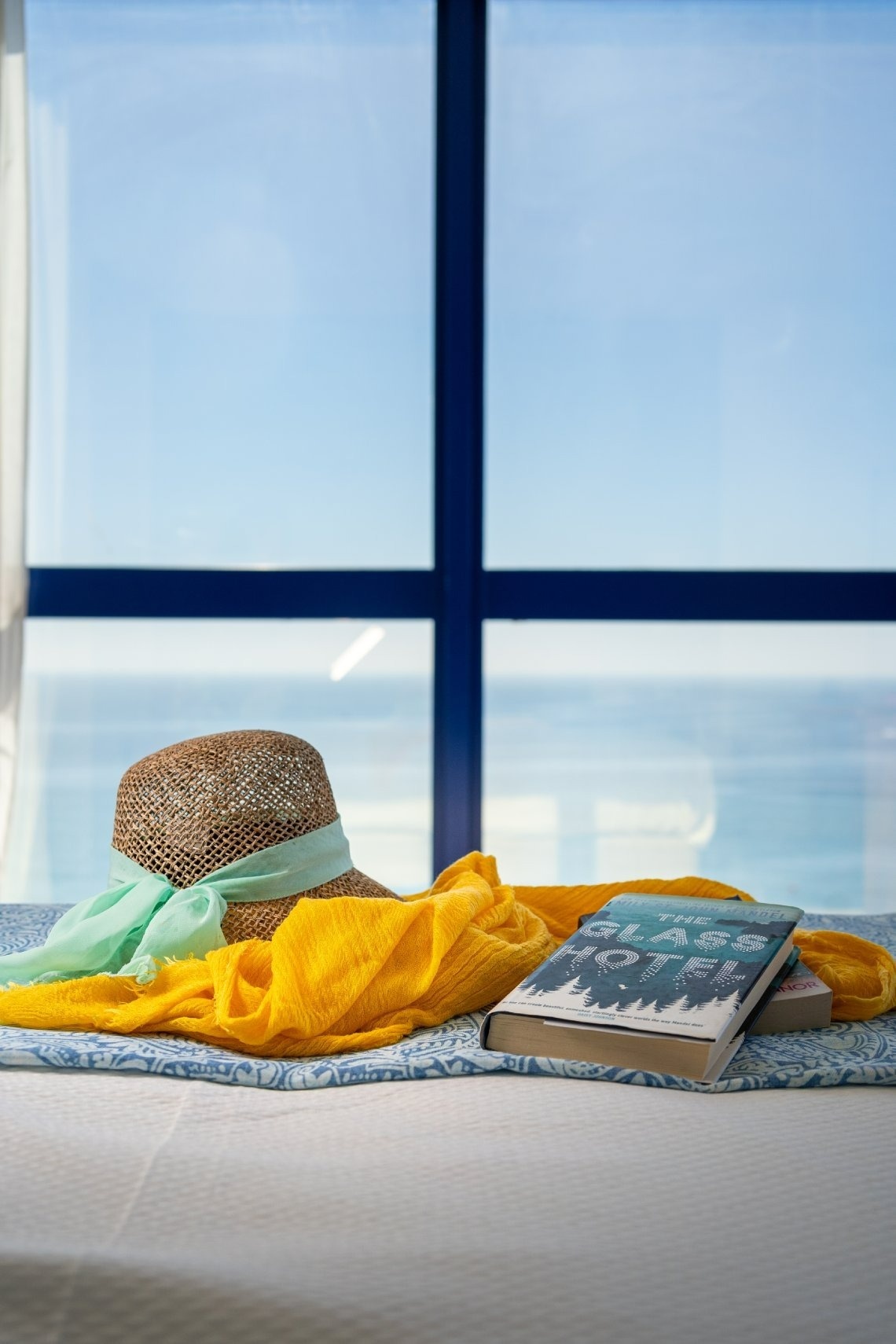 a book on a bed with a view of the ocean