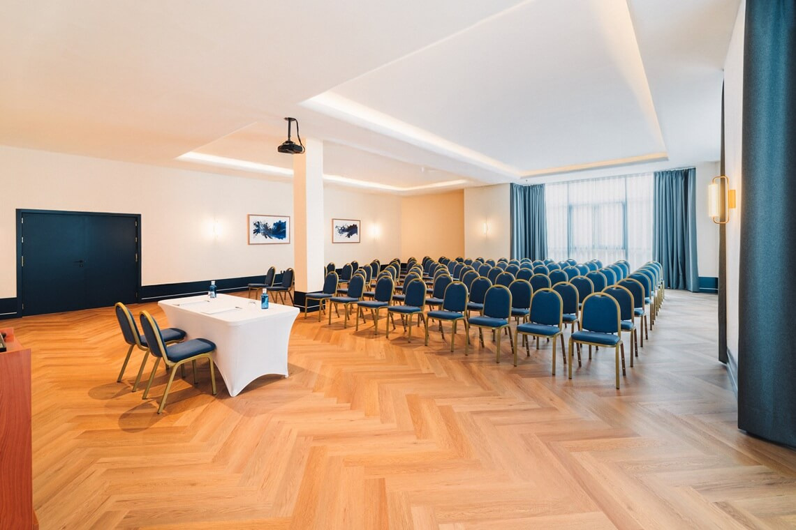 Empty conference room with rows of blue chairs and a presentation table, ideal for Yaramar events.