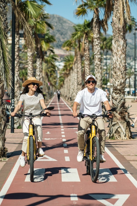 a man and a woman are riding bicycles down a street