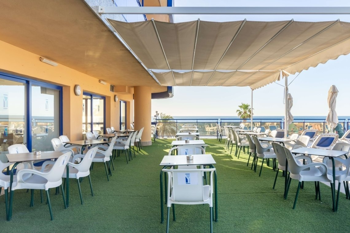 une terrasse avec des tables et des chaises et un parasol