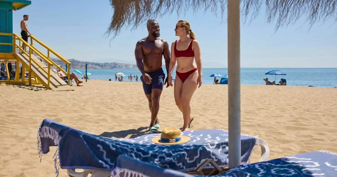 Couple en maillot de bain se promenant sur la plage de notre hôtel Yaramar.