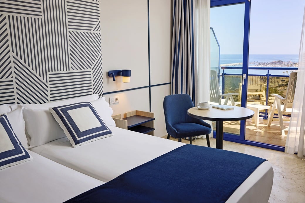 A modern hotel room with a view of the sea, featuring twin beds and a small dining table. Rooms | Hotel Yaramar | Fuengirola | Malaga | Official Web