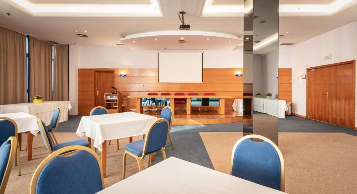 a conference room with tables and chairs and a projector screen