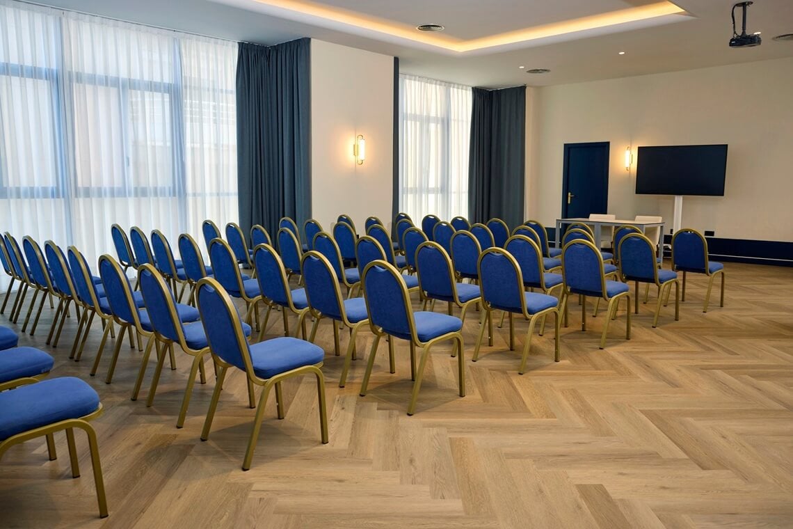 Alboran Room Conference room with blue chairs and a screen, ideal for Yaramar.