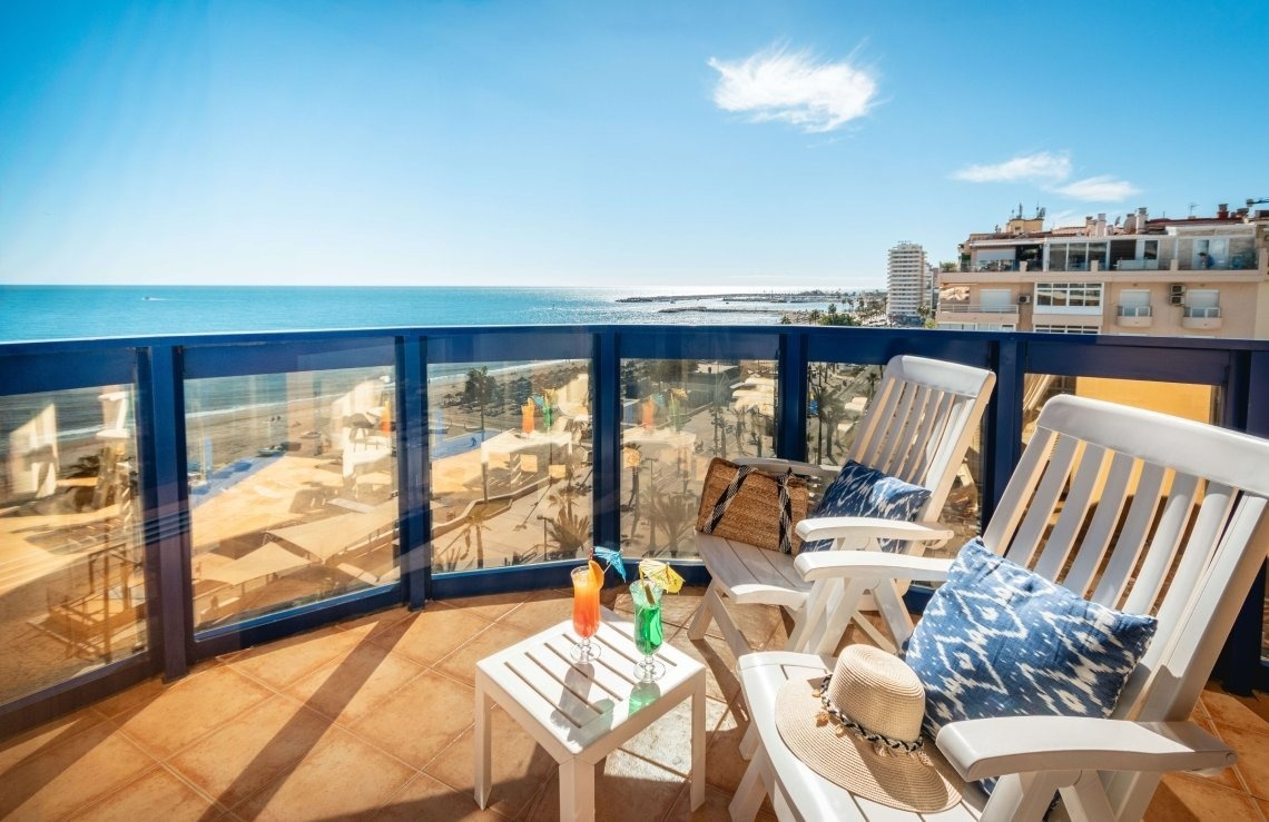 a balcony with two chairs and a table with a drink on it