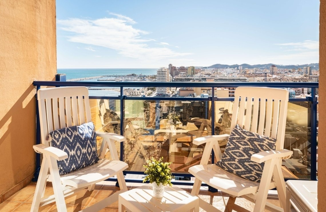 dos sillas y una mesa en un balcón con vista al océano