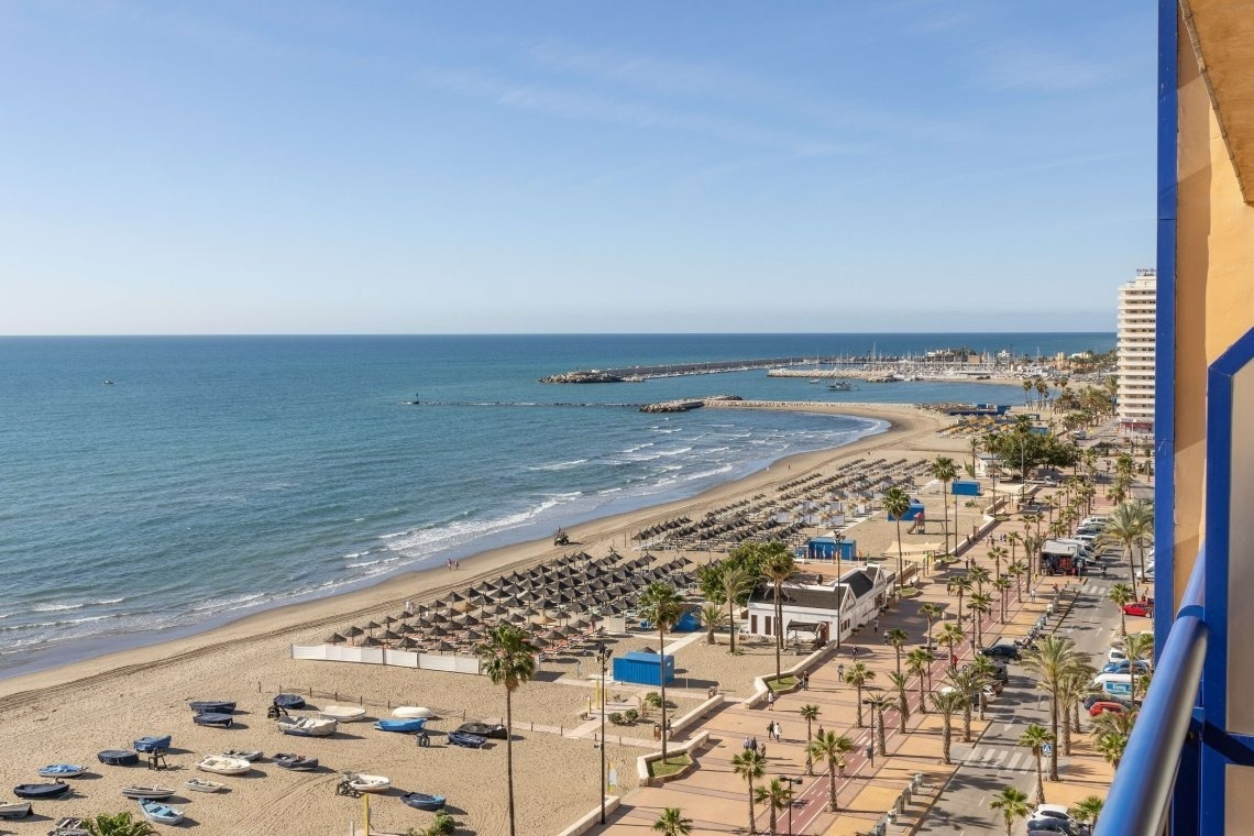 a view of a beach from a balcony with a blue railing