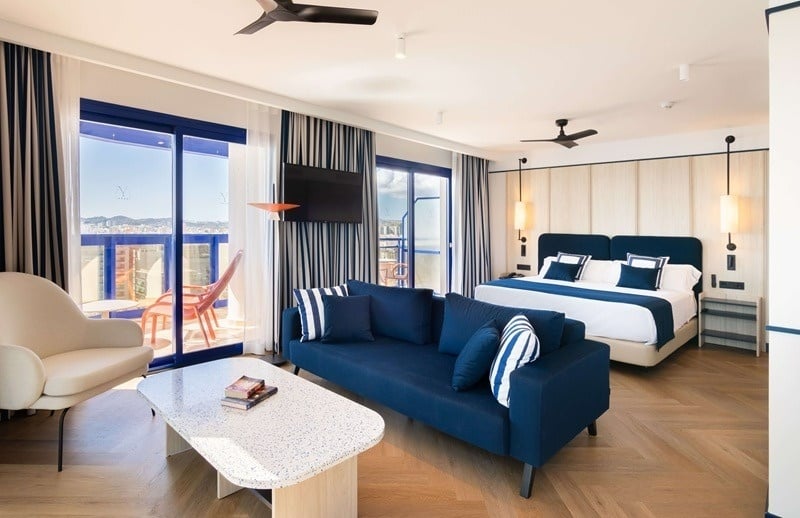 Una habitación moderna y luminosa con vistas al mar, decorada con motivos náuticos en tonos azules y blancos.
