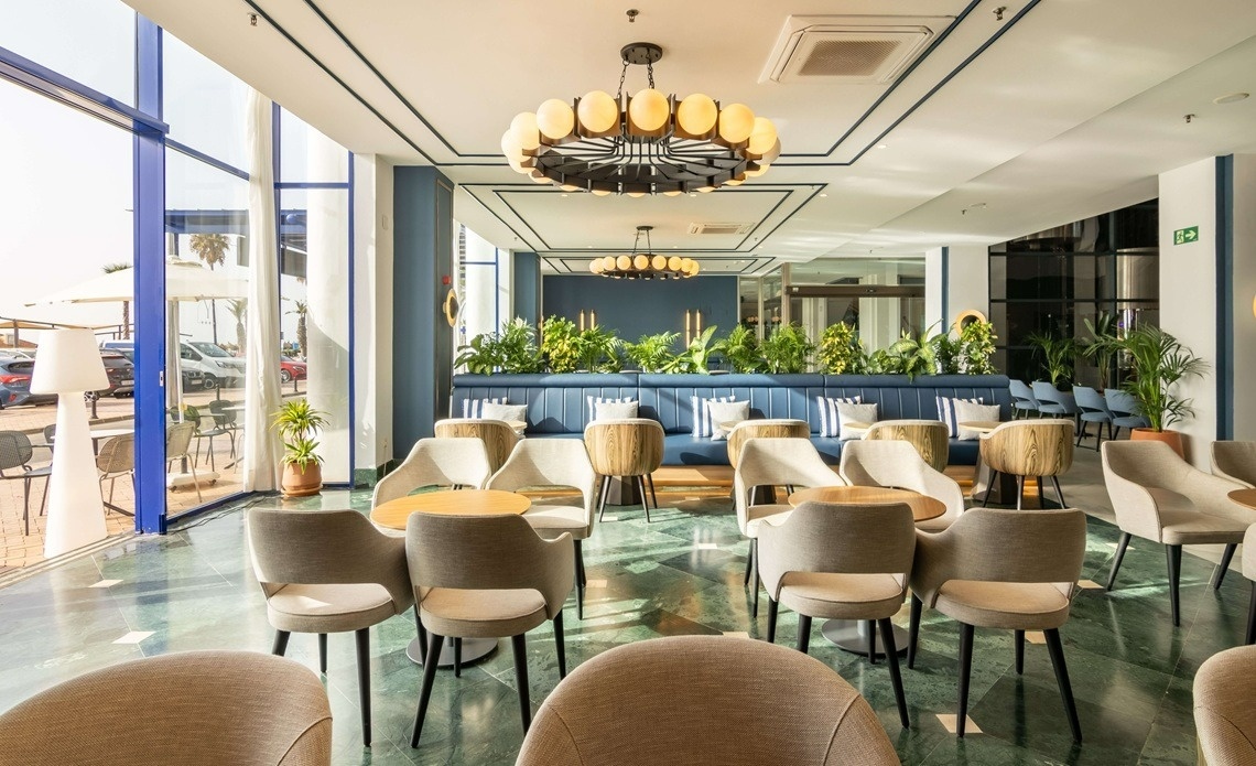 a long hallway with red chairs and a chandelier
