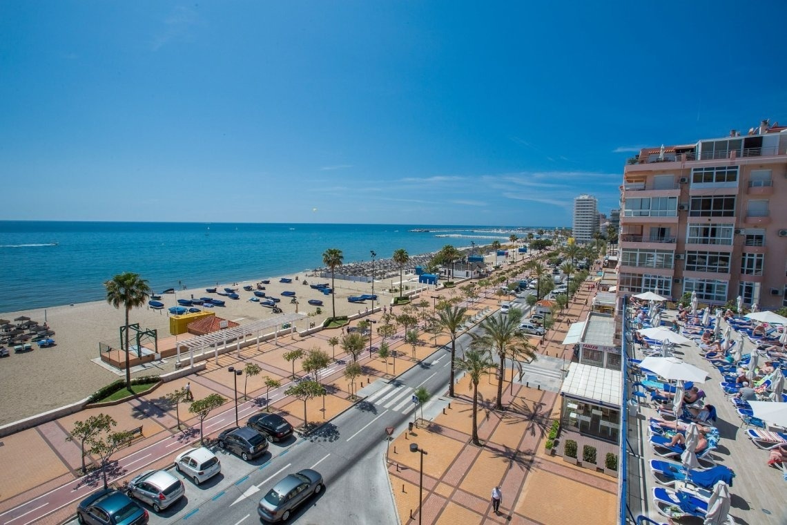 una vista aérea de una playa con coches estacionados al costado de la carretera