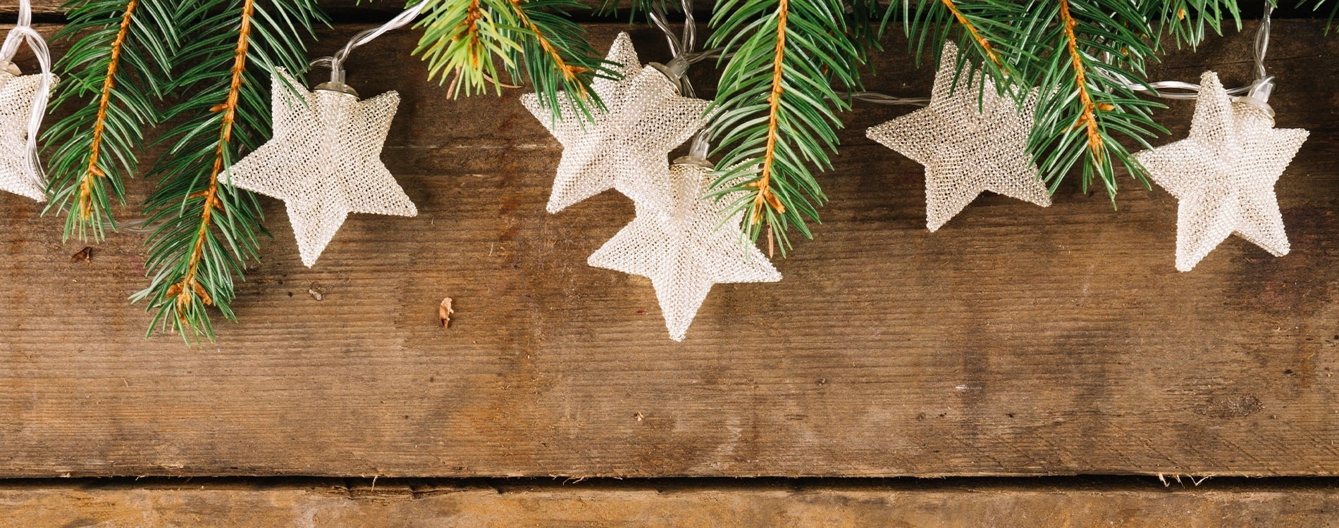 christmas decorations hanging from a string on a wooden wall