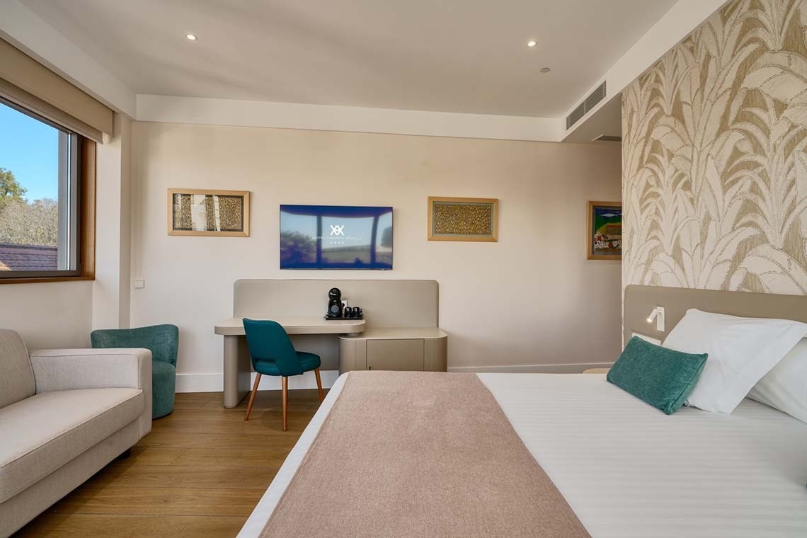 Una moderna y luminosa habitación de hotel equipada con cama, sofá, escritorio, televisión y una ventana que da al exterior.