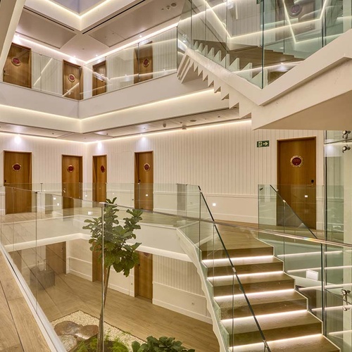 Modern Ybarra Sevilla hotel interior with glass railings, wooden floors, and multiple doors.
