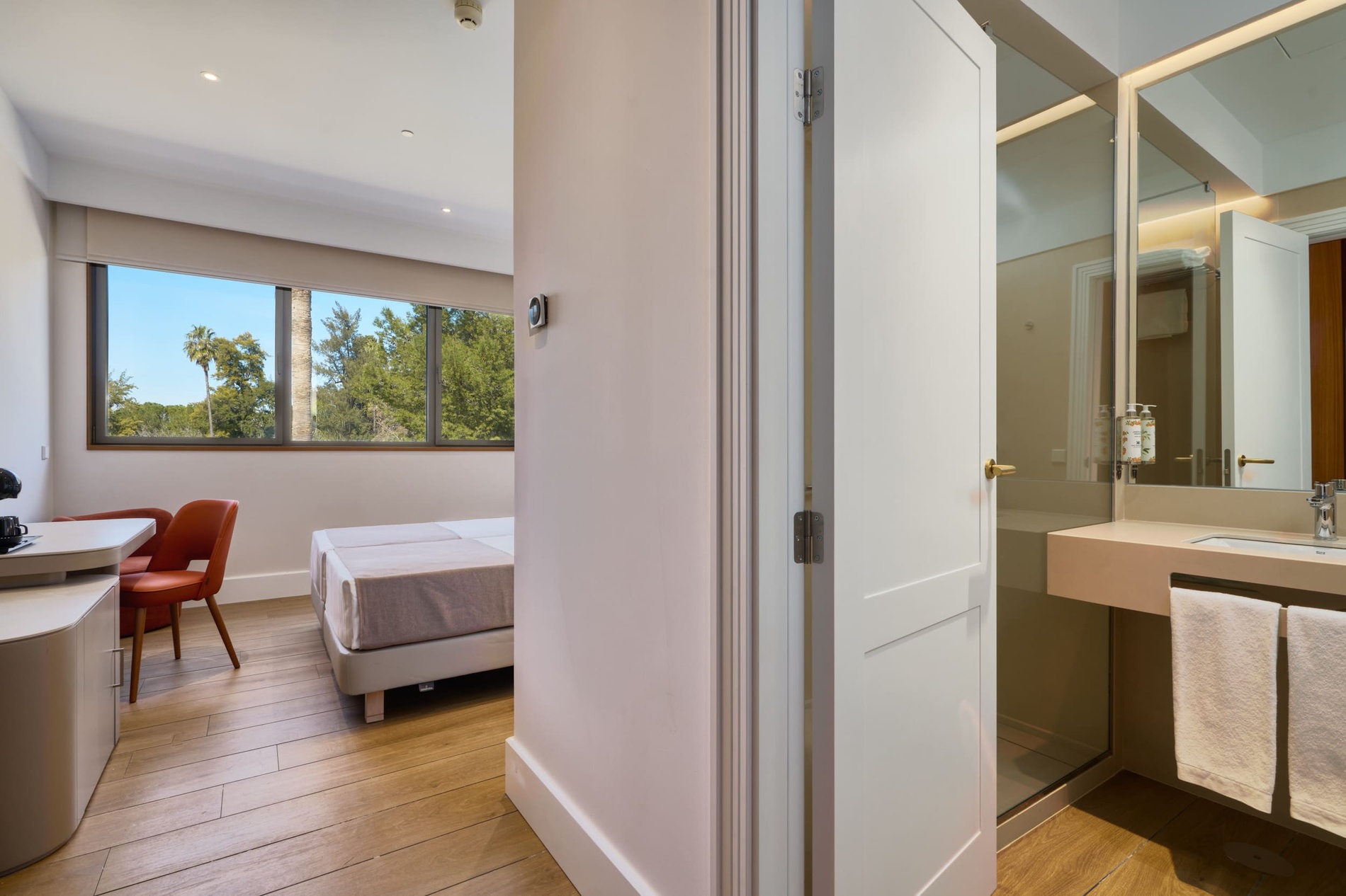 Bright hotel room in Ybarra Sevilla with park view, bed, desk, and modern bathroom.