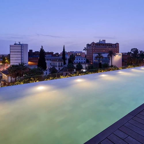 Rooftop pool at Hotel Ybarra Sevilla offers stunning city views at dusk.
