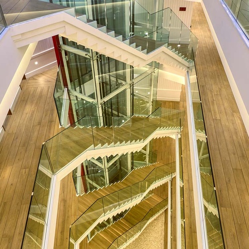Modern Ybarra Sevilla hotel interior with glass staircase and elevator.