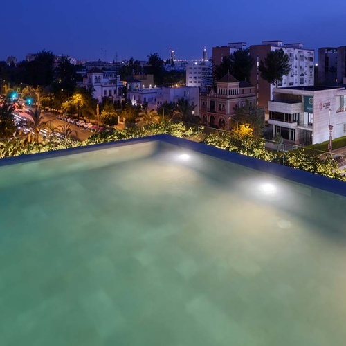 Rooftop pool at Hotel Ybarra Sevilla offers stunning city views at night.