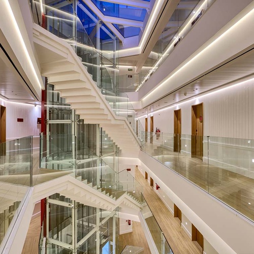 Modern hotel interior with glass railings, white staircase, and Ybarra Sevilla signage.