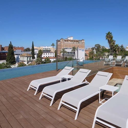 Ybarra Sevilla rooftop pool terrace with sun loungers and city views.