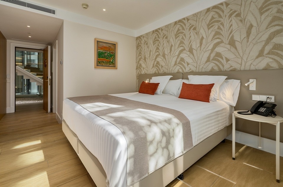 Habitación de hotel moderna con cama grande, decoración elegante y suelo de madera.