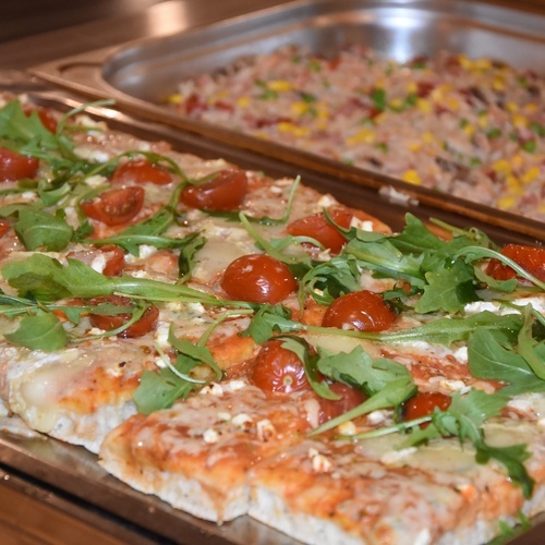 una pizza con tomates y queso en una bandeja de metal