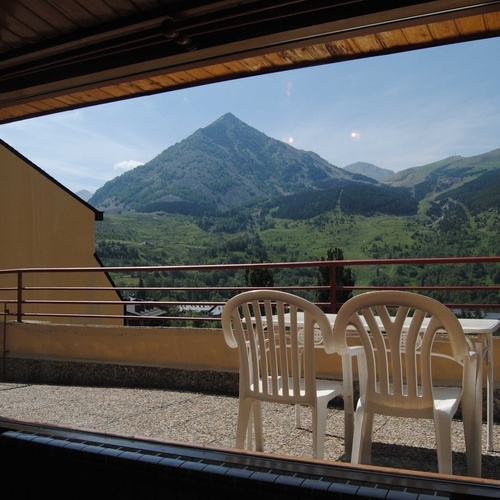 a view of a mountain from a balcony with a table and chairs