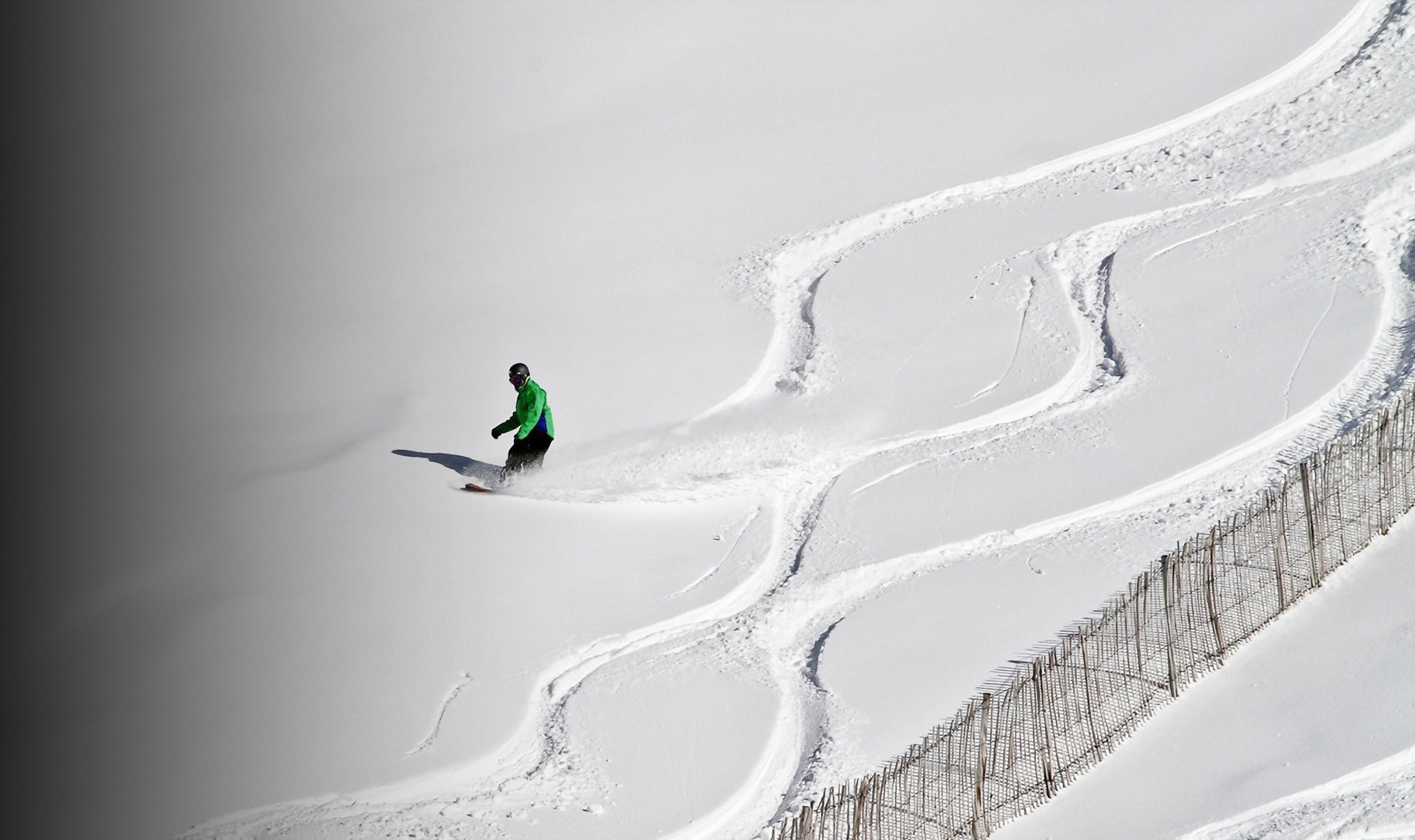 a person in a green jacket is skiing down a snowy slope