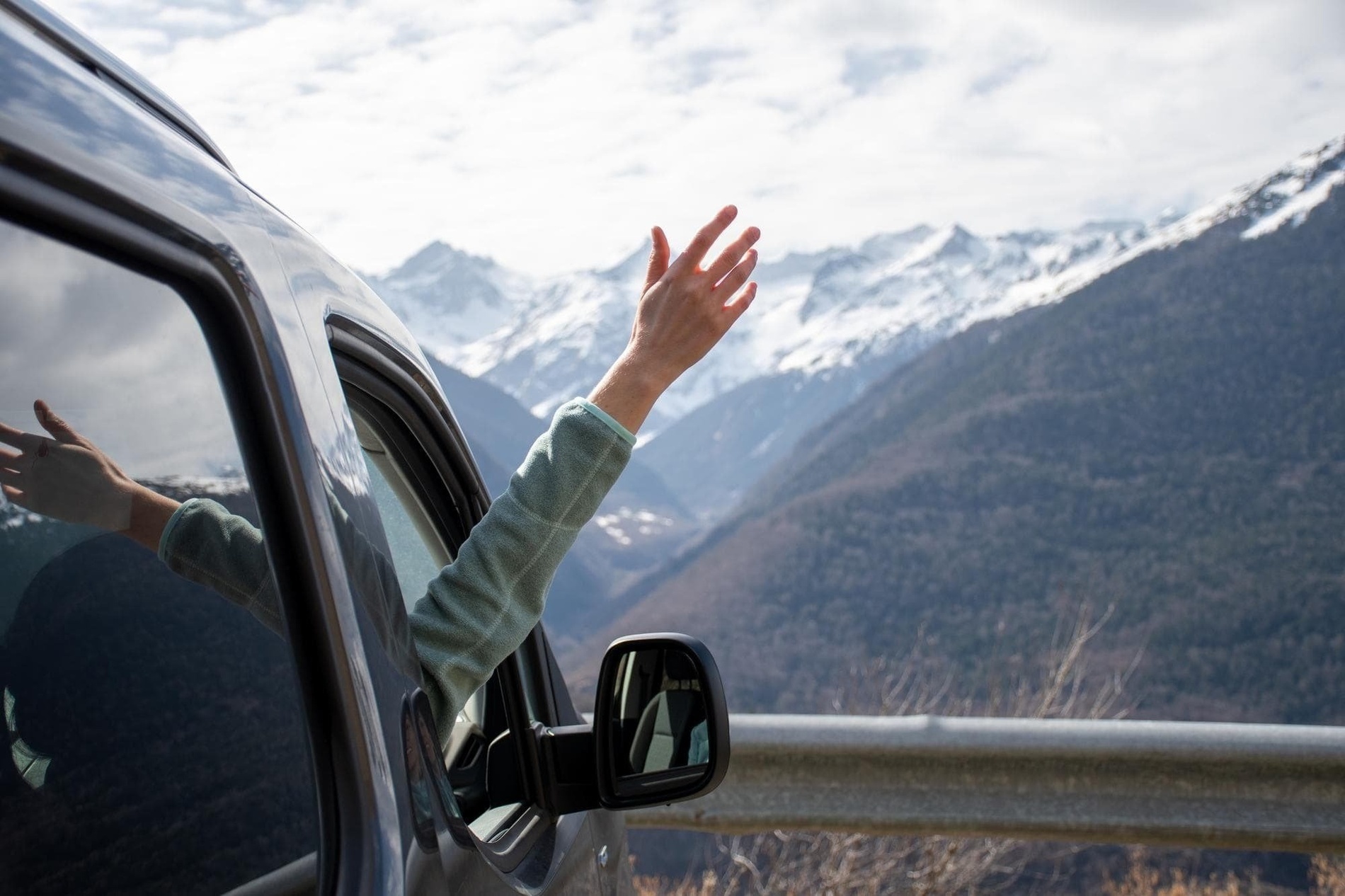 a person waving their hand out of a car window