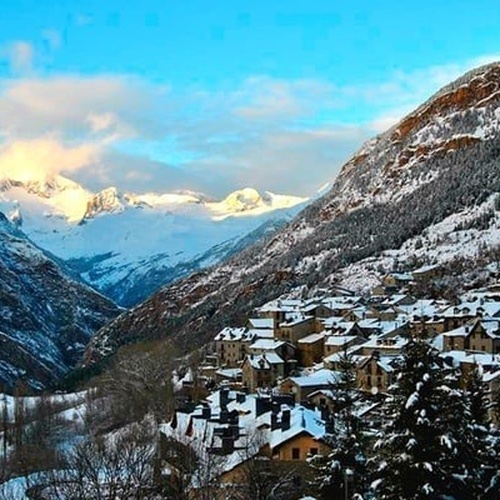 una pequeña ciudad está rodeada de montañas cubiertas de nieve .