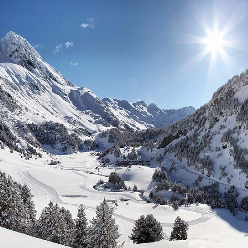 el sol brilla a través de las montañas cubiertas de nieve