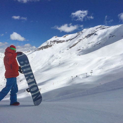 un hombre con una chaqueta roja sostiene una tabla de snowboard que dice burton