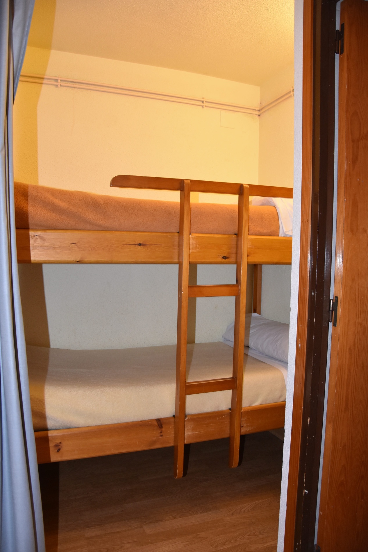 una habitación con dos literas de madera y una escalera