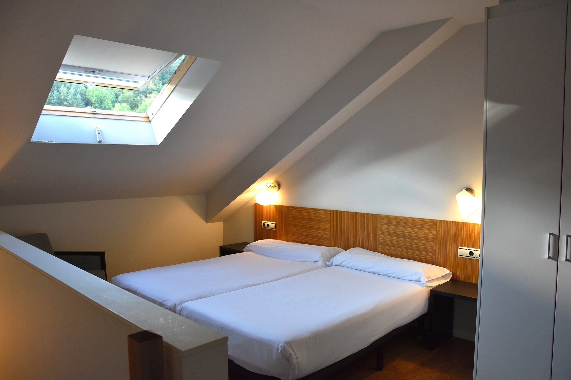 a bedroom with two beds and a skylight in the ceiling