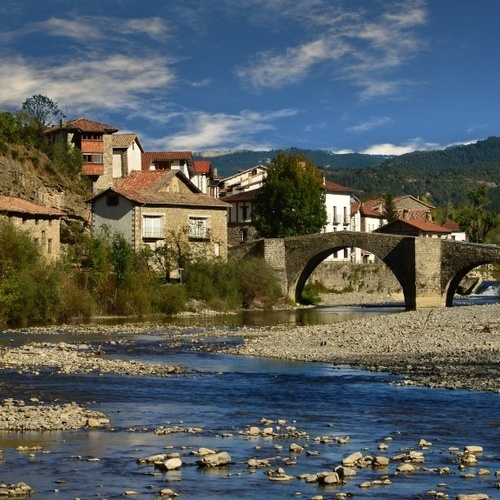a bridge over a river with mountains in the background