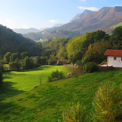 a white house with a red roof sits in the middle of a lush green field