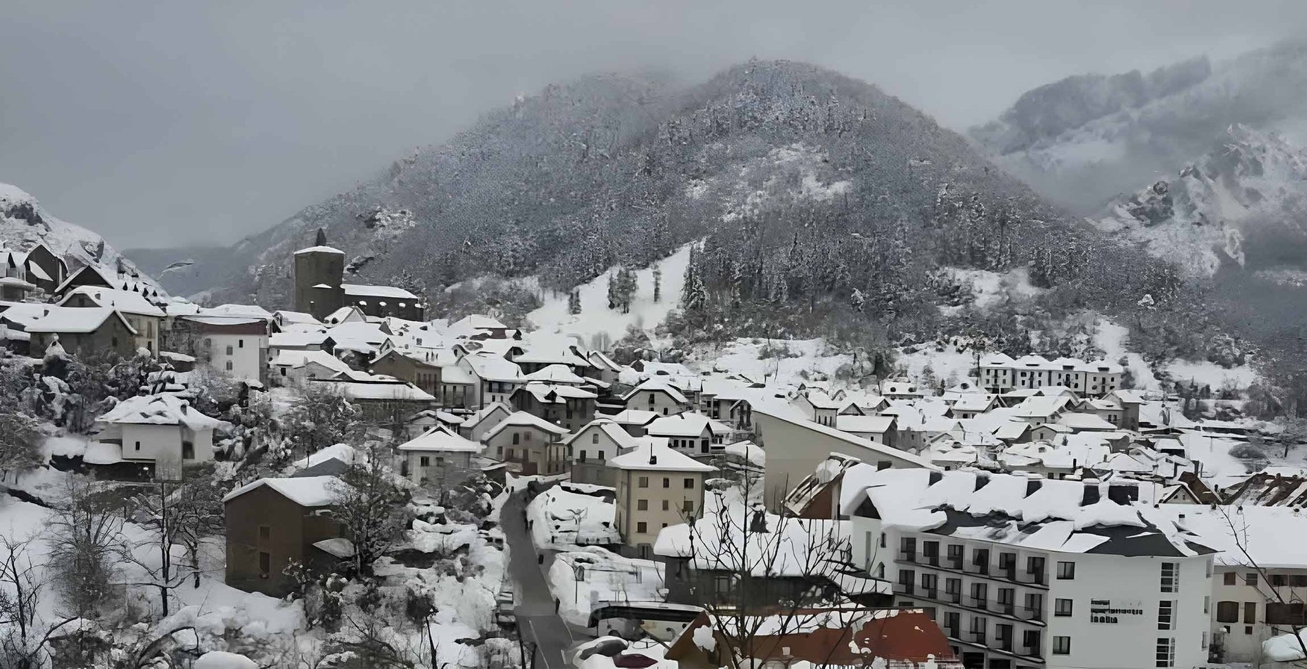 un pequeño pueblo cubierto de nieve con un edificio que dice " hotel "