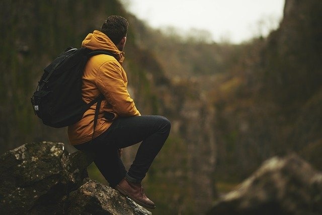 a man with a backpack is sitting on a rock