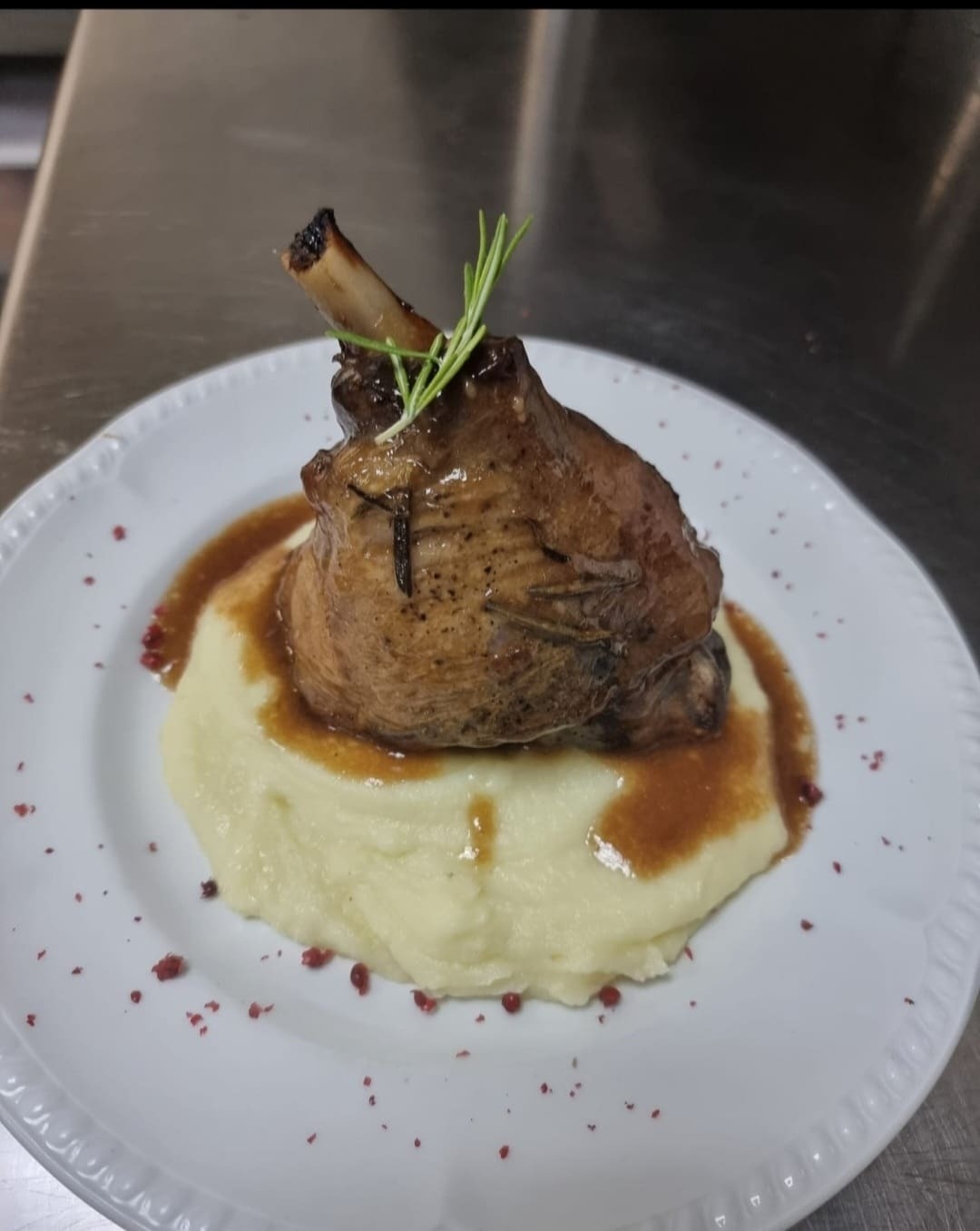 a white plate with a piece of meat on top of mashed potatoes