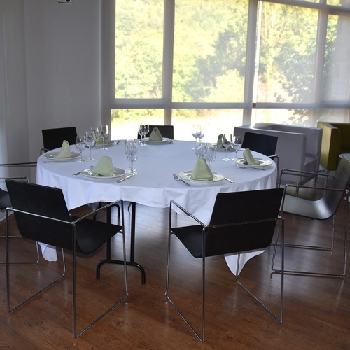 une table avec une nappe blanche est entourée de chaises noires