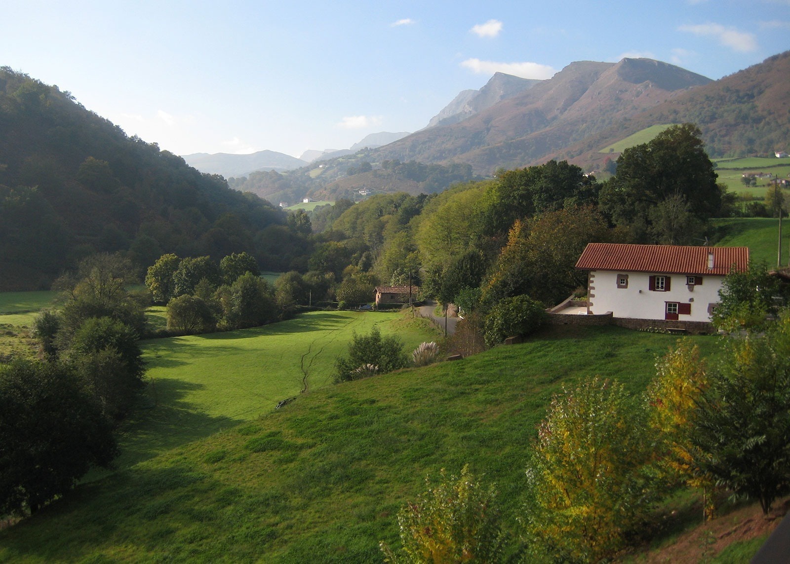 una casa blanca con techo rojo está en medio de un campo verde