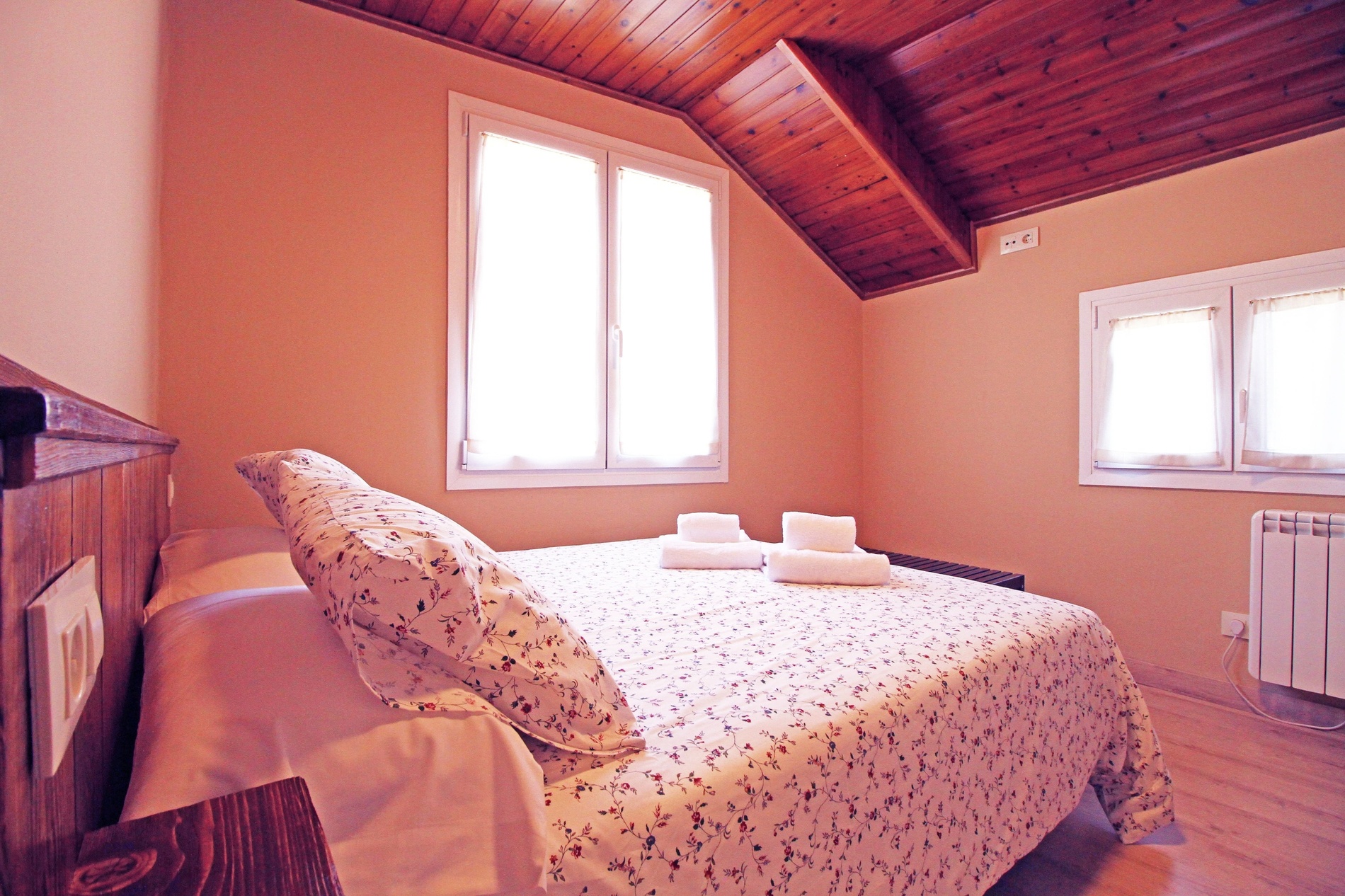 un dormitori rosa amb una cama i dues finestres