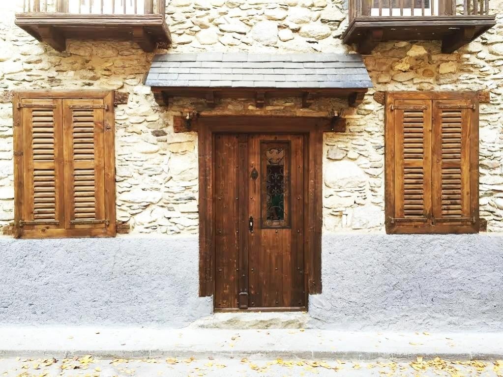 una puerta de madera y dos ventanas en una pared de piedra