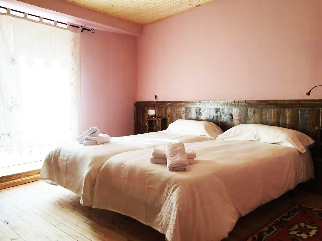 una habitación rosa con dos camas y una ventana