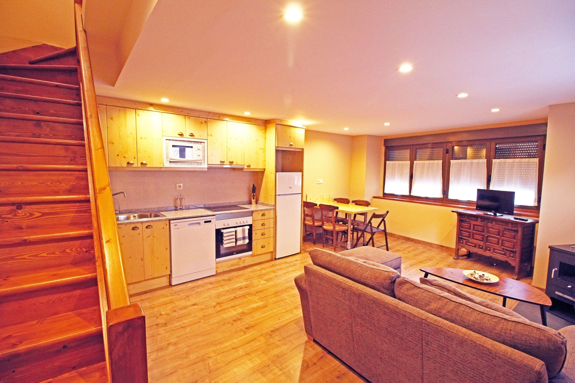 una cocina con electrodomésticos blancos y escaleras de madera