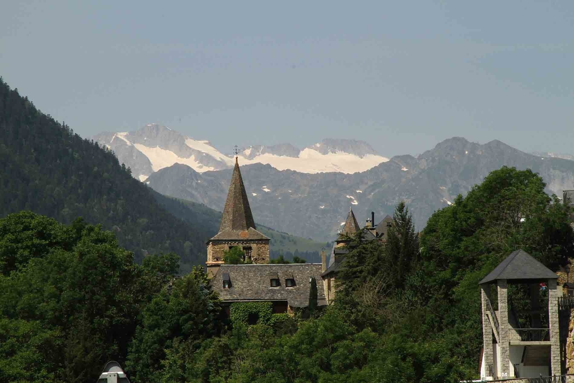 una iglesia en medio de un bosque con montañas en el fondo